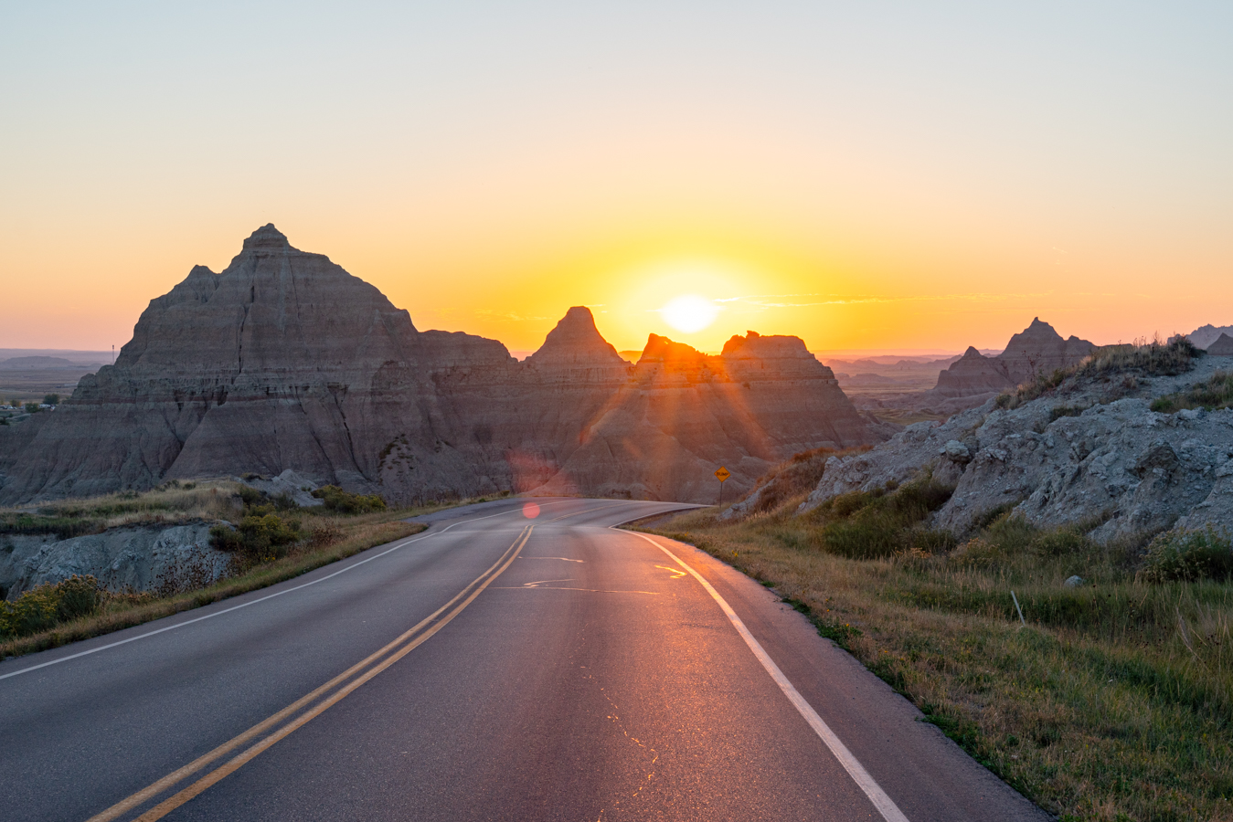 sunset over badlands loop in badlands national park with road front and center