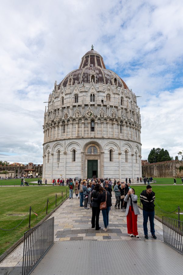 pisa baptistery with people in front of it on a cloudy day