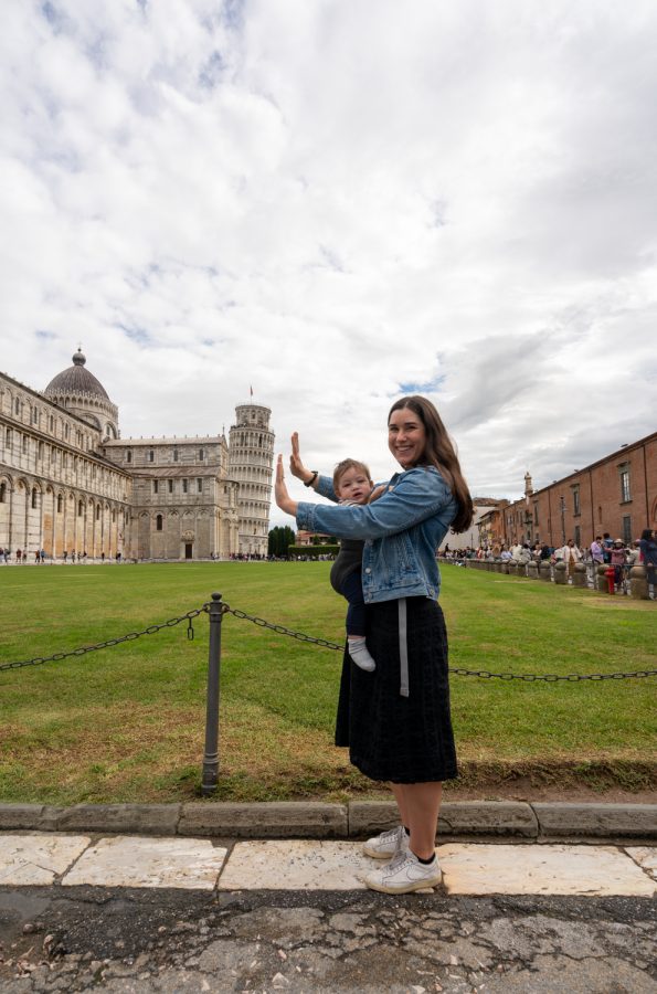 kate storm wearing her baby and holding up the leaning tower of pisa on a day trip to pisa from florence