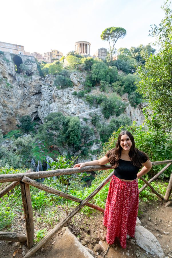 kate storm standing in villa gregoriana with temple and waterfall behind her